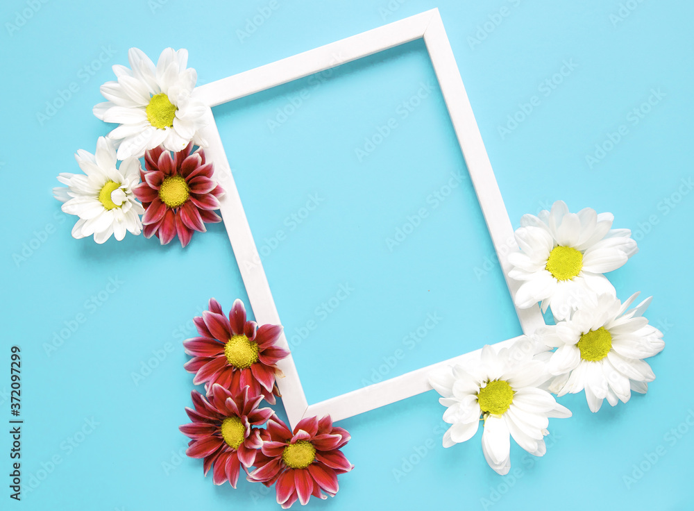Mockup square white frame with white and red flowers on blue background. View top. Messege or invitation card mock-up concept. flower layut. copy space for text Mockup square white frame with white and red flowers on blue background. View top. Messege or invitation card mock-up concept. flower layut. copy space for text