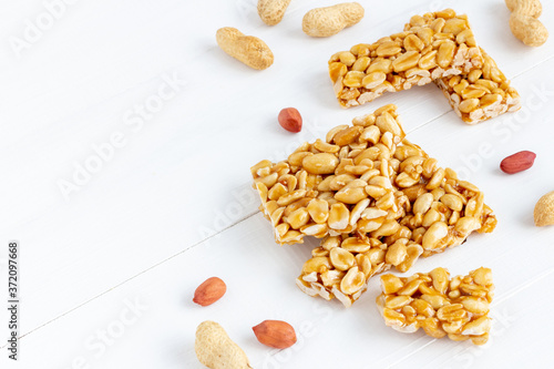 Plate of peanut brittle candy pieces on a white wooden background. photo