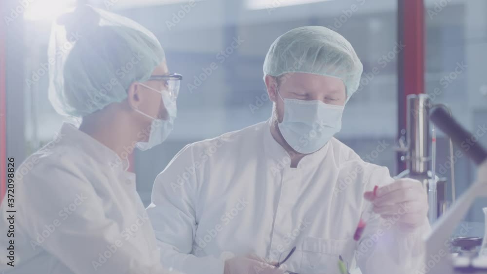 Medical colleagues discussing blood samples results in a modern laboratory Medical colleagues discussing blood samples results in a modern laboratory