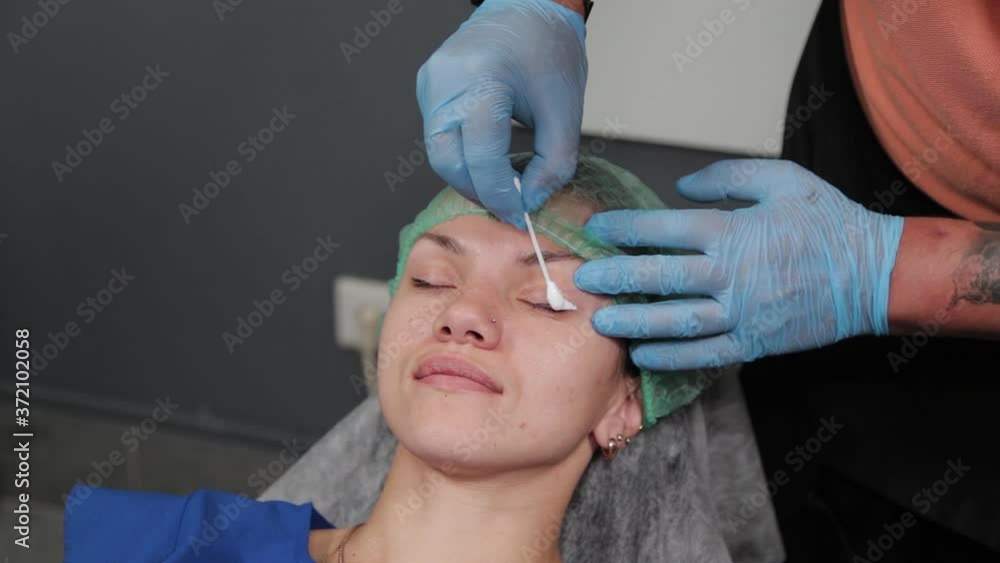 The permanent makeup artist applies an anesthetic to the lashes. The permanent makeup artist applies an anesthetic to the lashes.