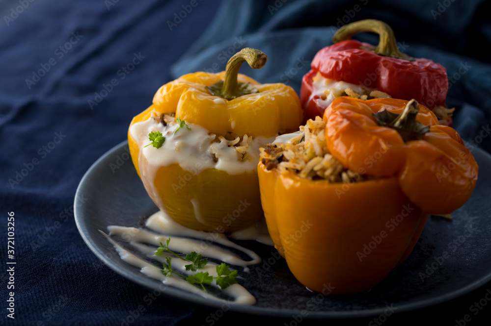 Colorful baked bell peppers stuffed with mince and rice on blue background