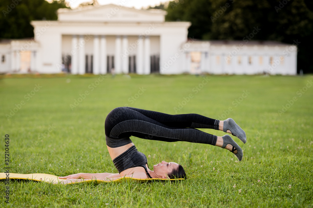 Beautiful young woman lying on a yellow mattress doing pilates or yoga, boomerang exercises