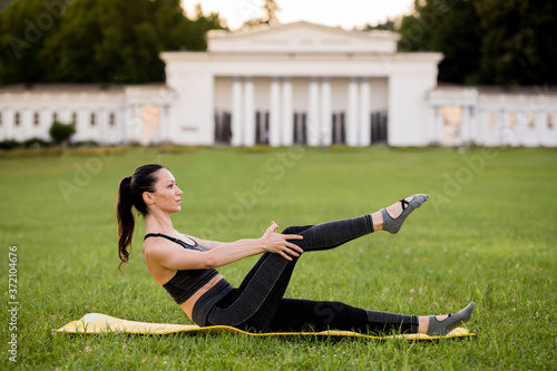 Beautiful young woman lying on a yellow mattress doing pilates or yoga, climb the tree exercises