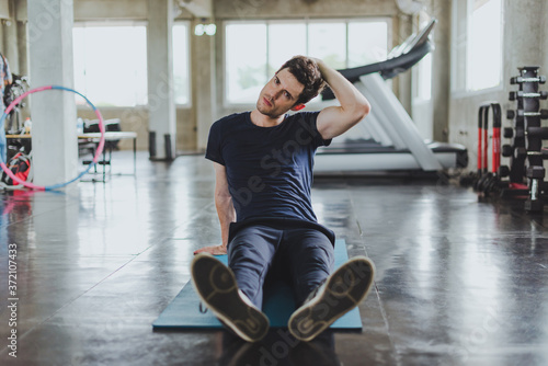 Athletic men stretching before exercising on yoga mats in the gym. By stretching his neck muscles.