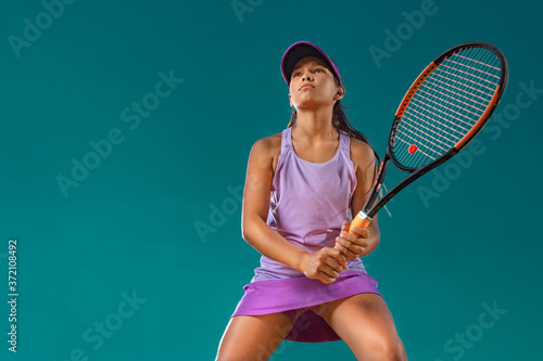 Teenager tennis player. Beautiful girl athlete with racket in pink sporswear and hat on tennis court. Fashion and sport concept.