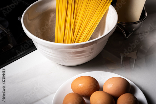 Preparing Spaghetti Carbonara on a black stove with eggs and pasta