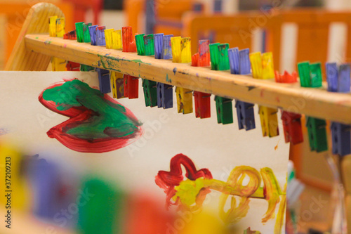 Bright artwork painted by Kindergarten children, hanging from pegs to dry in the classroom.