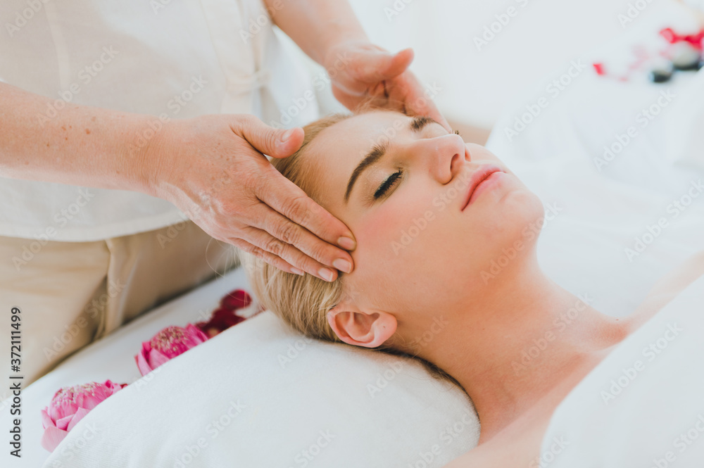 Beautiful woman lying on the bed for a spa asia massage at luxury spa and relaxation. The masseuse massaged her face and head in the spa room. Beautiful woman lying on the bed for a spa asia massage at luxury spa and relaxation. The masseuse massaged her face and head in the spa room.