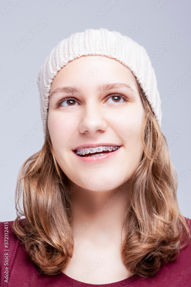 Fototapeta premium Teenage Ideas. Closeup Portrait of Positive Caucasian Teenager Girl Wearing Teeth Brackets. Posing Against Gray.