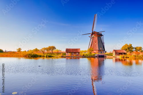 Netherlands Traveling. Traditional Dutch Windmill and Dutch Houses in Kinderdijk Village in the Netherlands At Daytime.