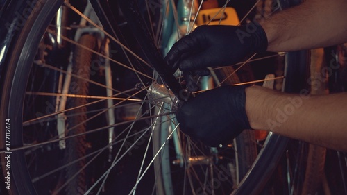 theme small business bike repair. A young Caucasian brunette man wearing safety glasses, gloves and an apron uses a hand tool for repairing and installing the bicycle's Modguards in a garage workshop