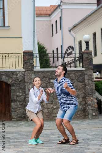 Vacations Travel Ideas. Happy Caucasian Couple Having Fun While Preparing To Jump Together During Traveling in The City.