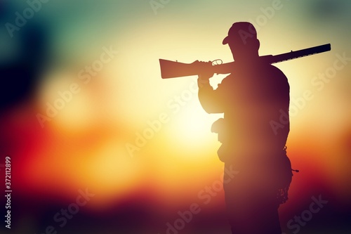 Fotografia Male hunter silhouette with a gun at sunset