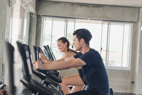 Male and female athletes talk about exercise, cycling in the gym. They wear sportswear to exercise.