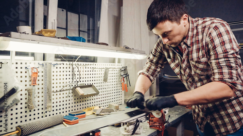 Wallpaper Mural Ski maintenence. Removing excess wax from race ski base plastic scraper. Ski service and repair. Winter shop worker doing base repair. Rental workshop service. Repairman In Workshop Ski Service Torontodigital.ca