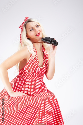 Portrait of Caucasian Blond Girl Posing in Pin-up Style. Sitting With Binoculars and Watching Forward with Positive Facial Expression.