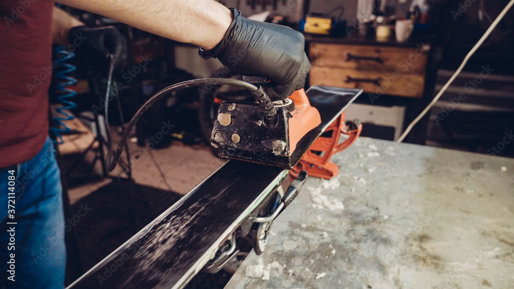 Applying hot wax to ski base with iron. Applying Ski Wax To Ski Base. Ski base tuning. Ski wax iron and wax bars. Ski service and repair. repairman in workshop ski service. Man Waxing Ski In Workshop Applying hot wax to ski base with iron. Applying Ski Wax To Ski Base. Ski base tuning. Ski wax iron and wax bars. Ski service and repair. repairman in workshop ski service. Man Waxing Ski In Workshop