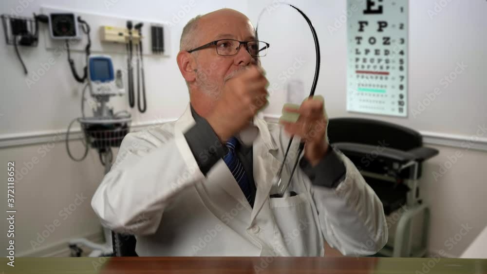 Male doctor wearing a lab coat and stethoscope in exam room sitting at desk dealing with depression or grief. Male doctor wearing a lab coat and stethoscope in exam room sitting at desk dealing with depression or grief.