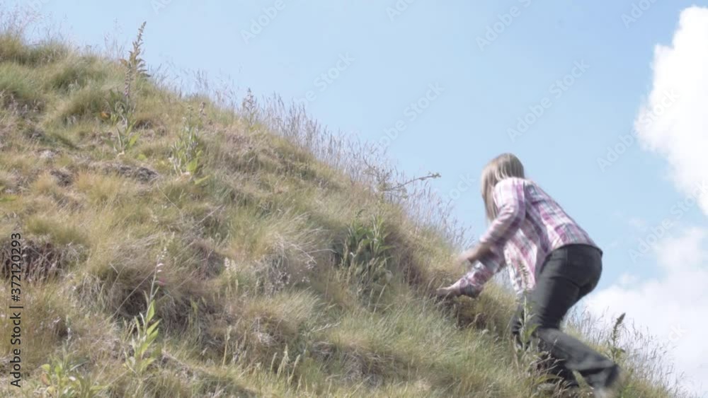 Woman climbing hill in rugged moorland Woman climbing hill in rugged moorland