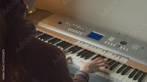 Young woman playing silver electric piano. Over shoulder shot