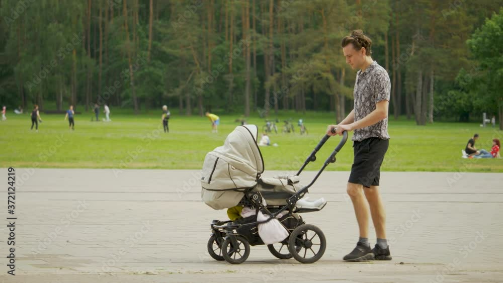 Young father takes care of his baby girl. Man walking outside with stroller. Young father takes care of his baby girl. Man walking outside with stroller.