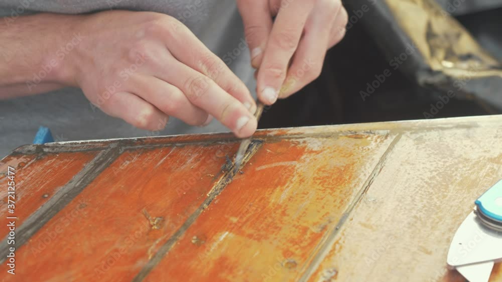 Scraping out old sikaflex making repair to wooden boat wheelhouse roof planking Scraping out old sikaflex making repair to wooden boat wheelhouse roof planking