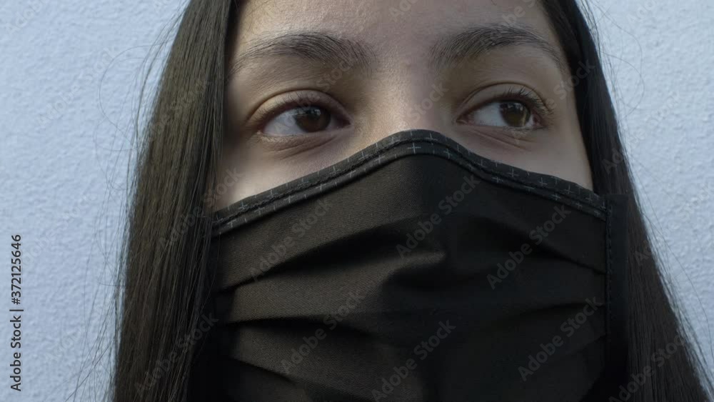Female Teenager Wearing Cotton Face Mask Against White Wall. Locked Off, Close Up Female Teenager Wearing Cotton Face Mask Against White Wall. Locked Off, Close Up