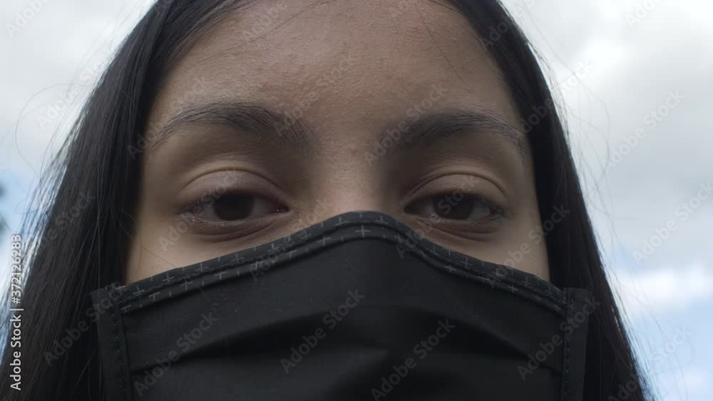Female Teenager Wearing Face Mask Against Blue Sky And Clouds. Looking At Camera, Follow Shot