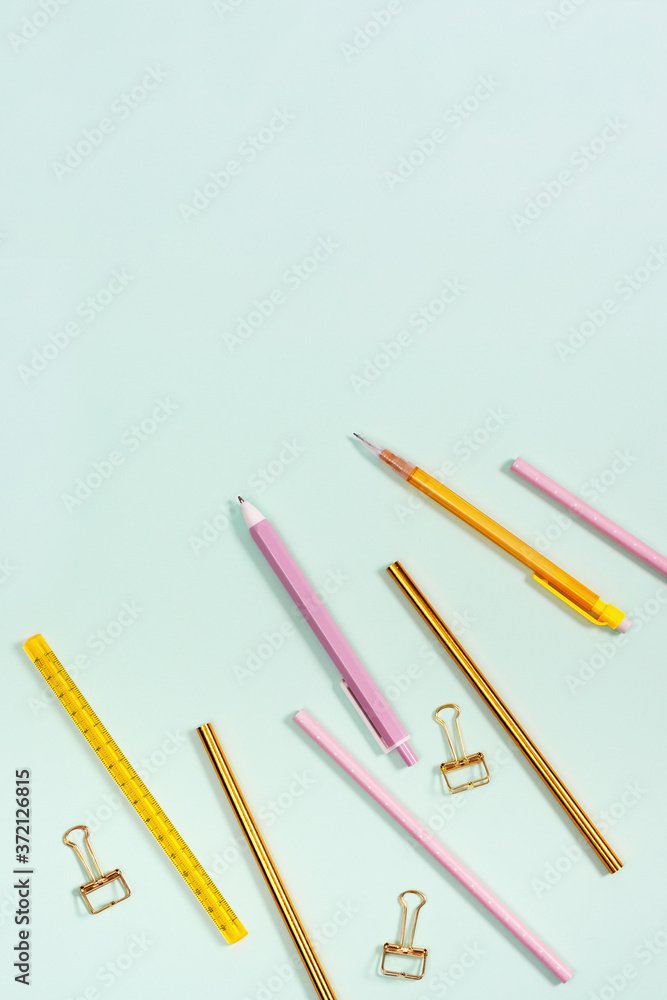 Flat lay with stationery for school or office. Pink and golden colored pencils, pens and metal paperclips. Flat lay with stationery for school or office. Pink and golden colored pencils, pens and metal paperclips.