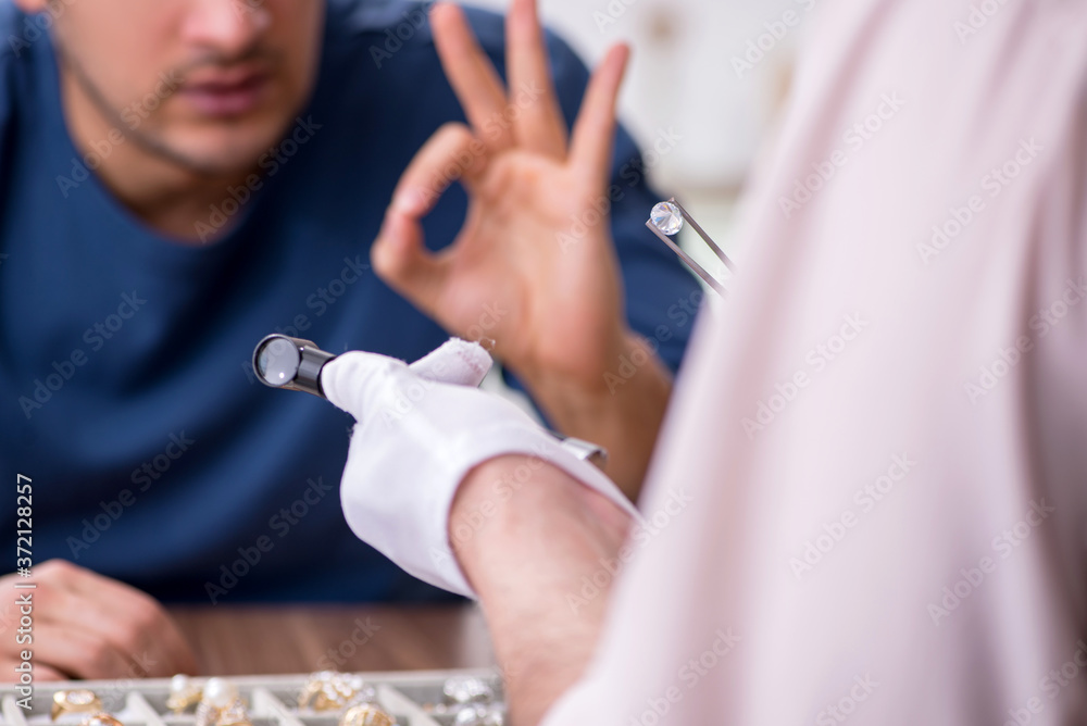 Young man visiting old male jeweler