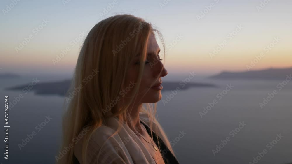 Blond woman smiling and watching sunset over island Santorini Greece Blond woman smiling and watching sunset over island Santorini Greece
