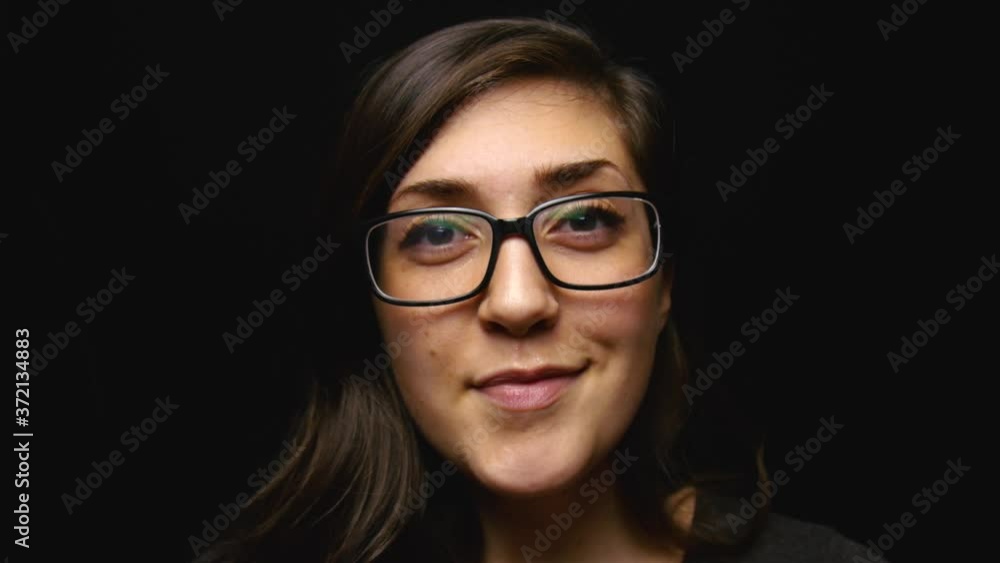 Woman puts on prescription glasses and smiles into camera. Woman puts on prescription glasses and smiles into camera.