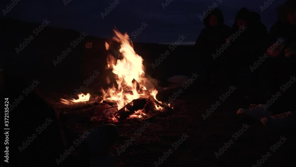 Young people sitting around a campfire enjoying leisure time in Iceland Young people sitting around a campfire enjoying leisure time in Iceland