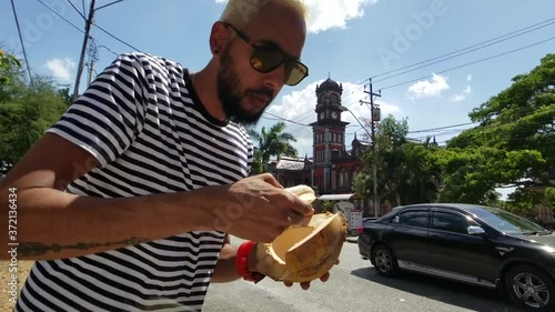 Man enjoying a fresh Coconut at the Queen's Park Savannah in Trinidad and Tobago photo