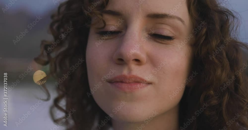 Pretty young woman with curly red hair shyly looks into camera, close up Pretty young woman with curly red hair shyly looks into camera, close up