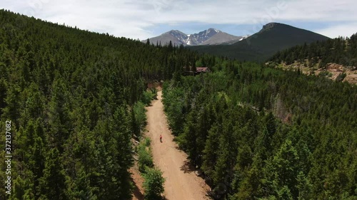 Mountain biker travels along Colorado dirt road trail with scenic mountain and forest