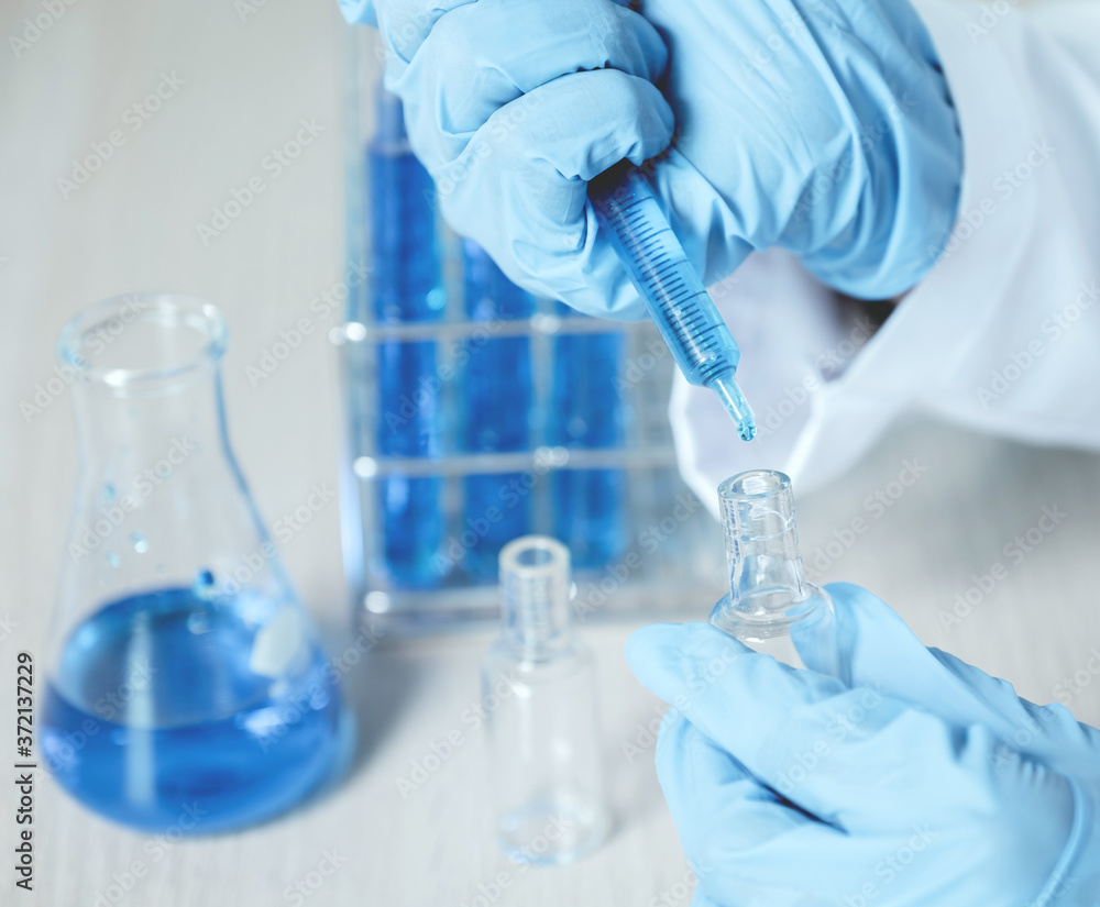 Fototapeta premium Doctors use a syringe to absorb vaccines, blue chemical liquid for research and analysis in a laboratory, to try and treat bacterial viruses