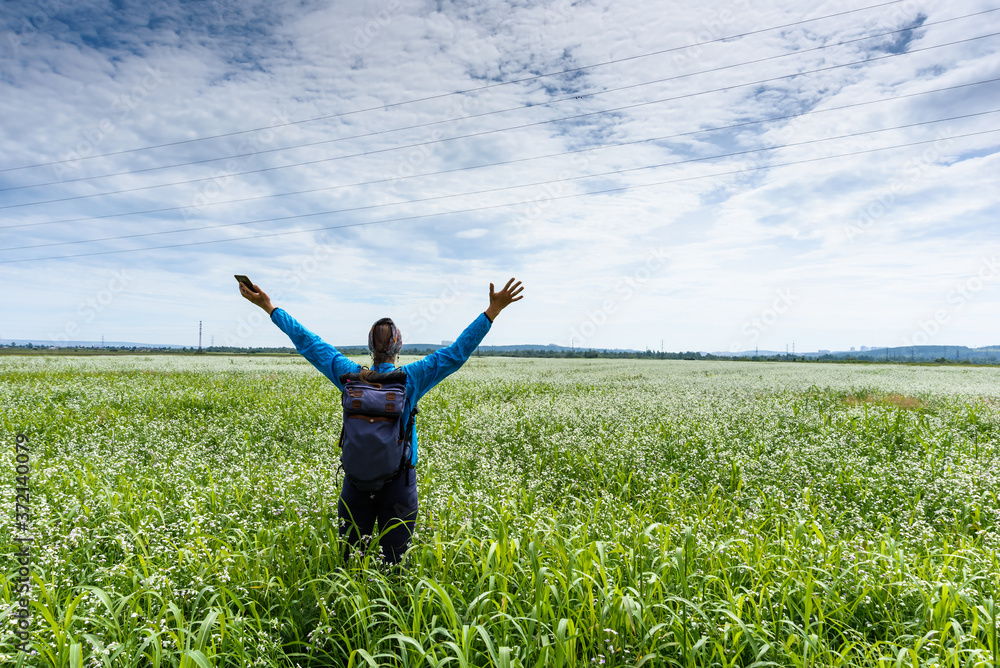 Women raises her hands and stays on a beautiful green meadow Women raises her hands and stays on a beautiful green meadow