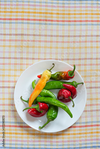 Hot red chili peppers in a white porcelain plate, put on an orange, red  and blue stripped napkin photo