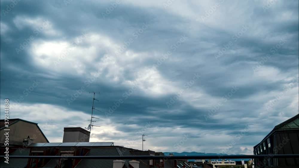 An immersive time lapse of dark swirling low level nimbostratus, stratus and cumulus clouds pass over rooftops and buildings during a summer thunderstorm. The clouds pass quickly in high winds. An immersive time lapse of dark swirling low level nimbostratus, stratus and cumulus clouds pass over rooftops and buildings during a summer thunderstorm. The clouds pass quickly in high winds.