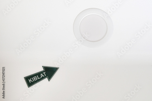 Kiblat arrow sign pointing to the direction of the Kaaba in Mecca, Saudi Arabia, seen on the ceiling of a room guiding Muslims on the direction they must face during their daily prayers. photo