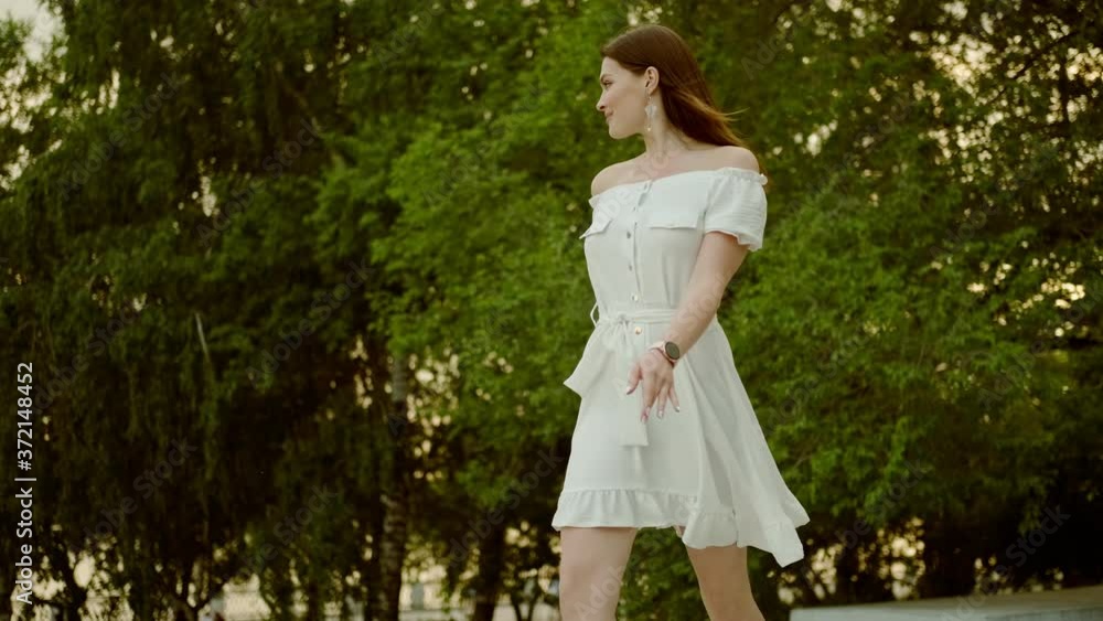 Young charming woman walking in a summer park at sunset Young charming woman walking in a summer park at sunset
