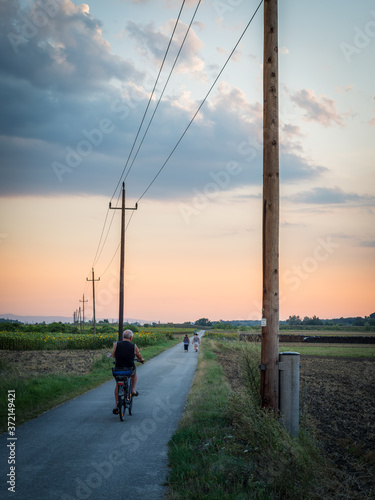 Cyclist riding along a road into sunset