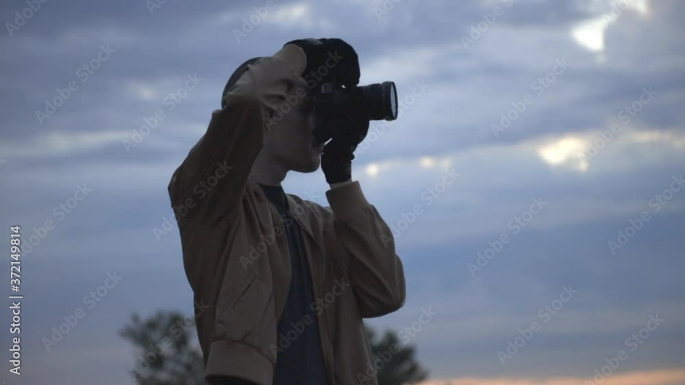 Young Guy In Brown Coat Taking Pictures With His Camera At The Beach - Medium Shot (Slow Motion) Young Guy In Brown Coat Taking Pictures With His Camera At The Beach - Medium Shot (Slow Motion)