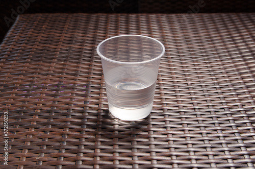 disposable plastic cup half filled with water on the brown table