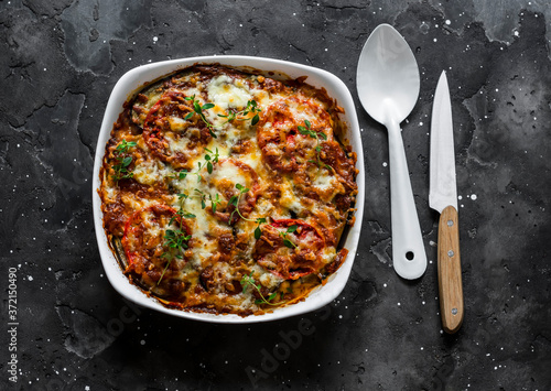 Italian Parmigiana. Eggplant, chicken, tomatoes, mozzarella cheese, tomato sauce casserole on a dark background, top view