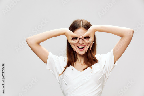 Woman holds her hands in front of her face in the form of a mask smile white dress emotions 