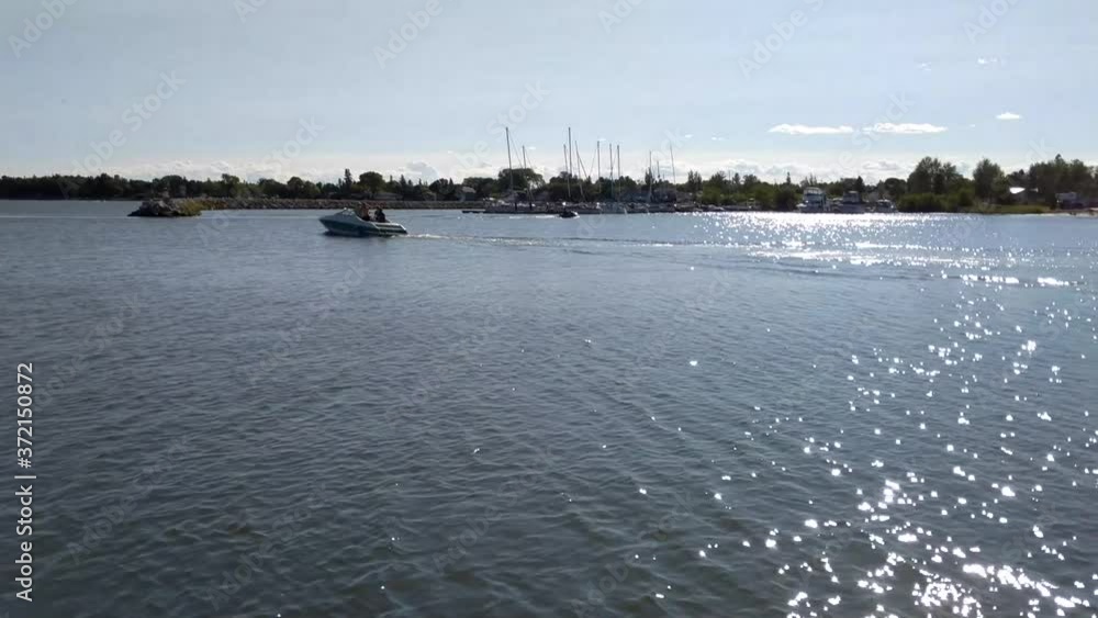 Boats slowly driving around a harbor on a sunny weekend in Gimli, Manitoba. Boats slowly driving around a harbor on a sunny weekend in Gimli, Manitoba.