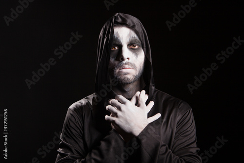 Spooky angel of death over black background with a hood. Halloween outfit.