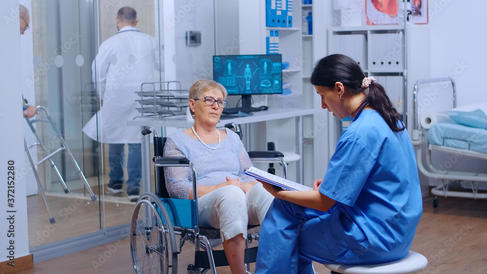 Obraz premium Elderly patient with walking disabilities in wheelchair seeking medical advice in recovery clinic or hospital. Senior handicapped woman health care support medical insurance paralyzed person